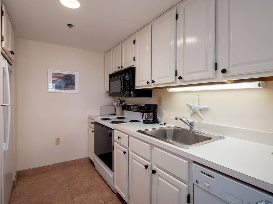 A kitchen with white cabinets, a microwave, stove, and a dishwasher.