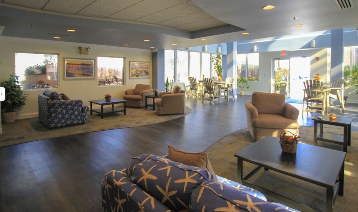 A spacious lobby with multiple seating areas, including sofas and chairs, and large windows providing natural light.