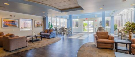 A spacious lobby with a curved seating area, wooden flooring, and large windows allowing natural light.