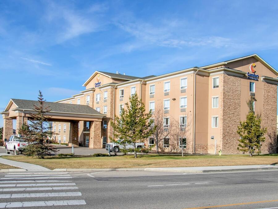 A multi-story hotel with a stone facade, a prominent sign, and a parking lot with vehicles.