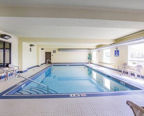 A swimming pool with a tiled deck, a lifeguard chair, and a no diving sign.