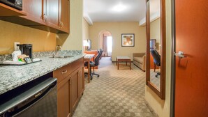 Una cocina de hotel con encimeras de granito, lavavajillas y armarios de madera.