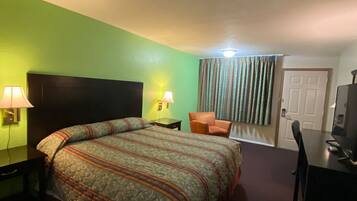A hotel room with a bed, a desk, a chair, and a television.