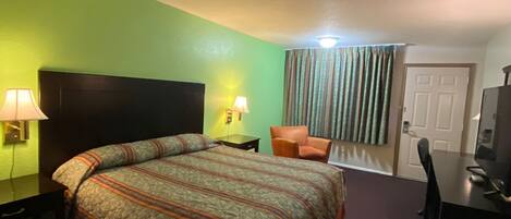 Une chambre d’hôtel avec un lit, un bureau, une chaise et un téléviseur.