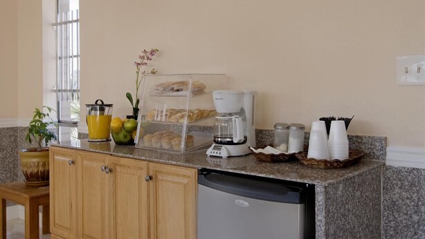 A kitchen with a coffee maker, a fruit bowl, a plant, and a bread display. - Sunrise Inn (Jasper)