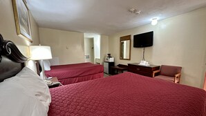 A hotel room with two beds, a desk, a chair, a television, and a mirror.
