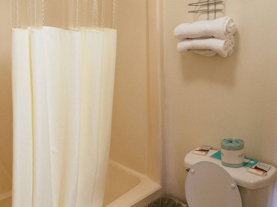 Et badeværelse med badekar, toilet og et håndklædestativ med håndklæder.