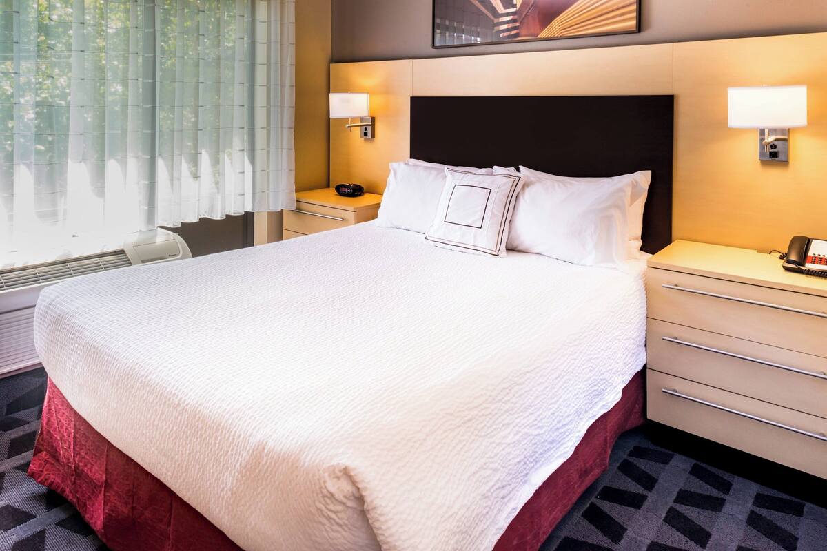 A hotel room with a large bed, two bedside tables, a desk, and a chair.