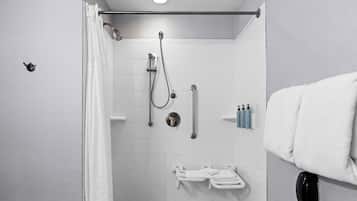 A shower area with a handheld showerhead, a wall-mounted faucet, and a towel rack with towels.