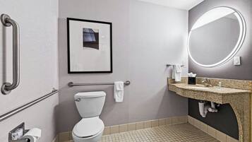 Un baño con inodoro, lavabo con espejo, toallero y un cuadro en la pared.