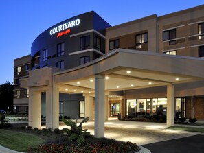 A Courtyard Marriott hotel with a modern design, featuring a covered entrance and a landscaped area with flowers. - Courtyard by Marriott Clarksville (Clarksville)