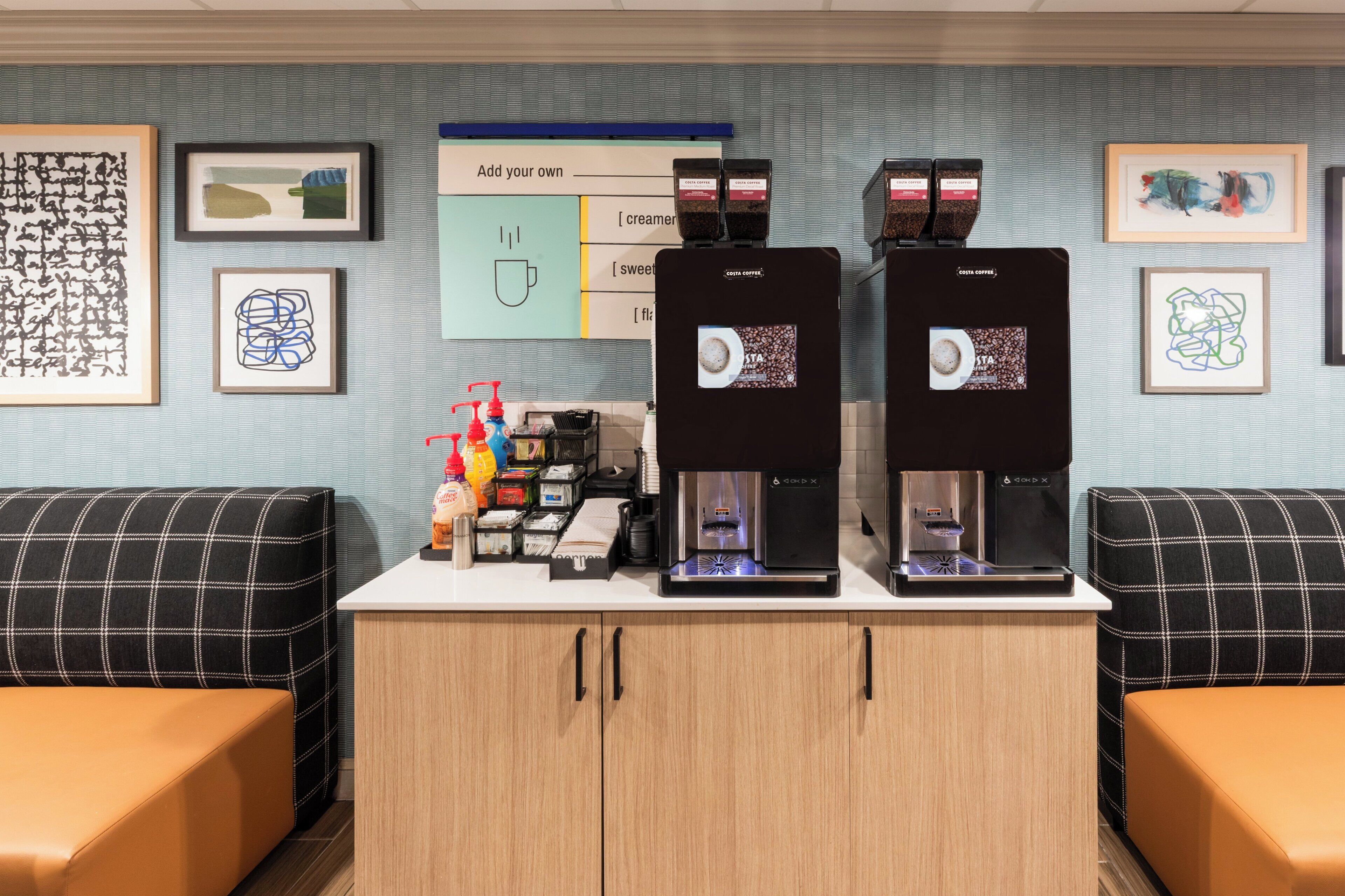 A coffee station with two espresso machines, a menu board, and various coffee-related items.