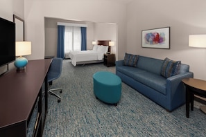 A hotel room with a bed, a sofa, a desk, and a TV. - Garner Hotel Norman - University Area by IHG (Norman)