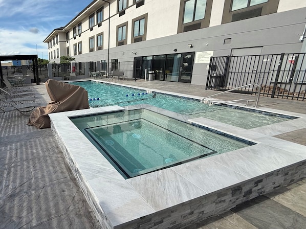 A rooftop pool with clear water, surrounded by lounge chairs and a covered seating area. - Garner Hotel Norman - University Area by IHG (Norman)