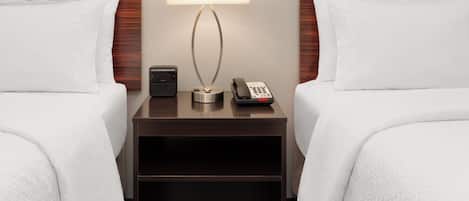 Habitación de hotel con dos camas, una mesita de noche, una lámpara, un teléfono y un control remoto.