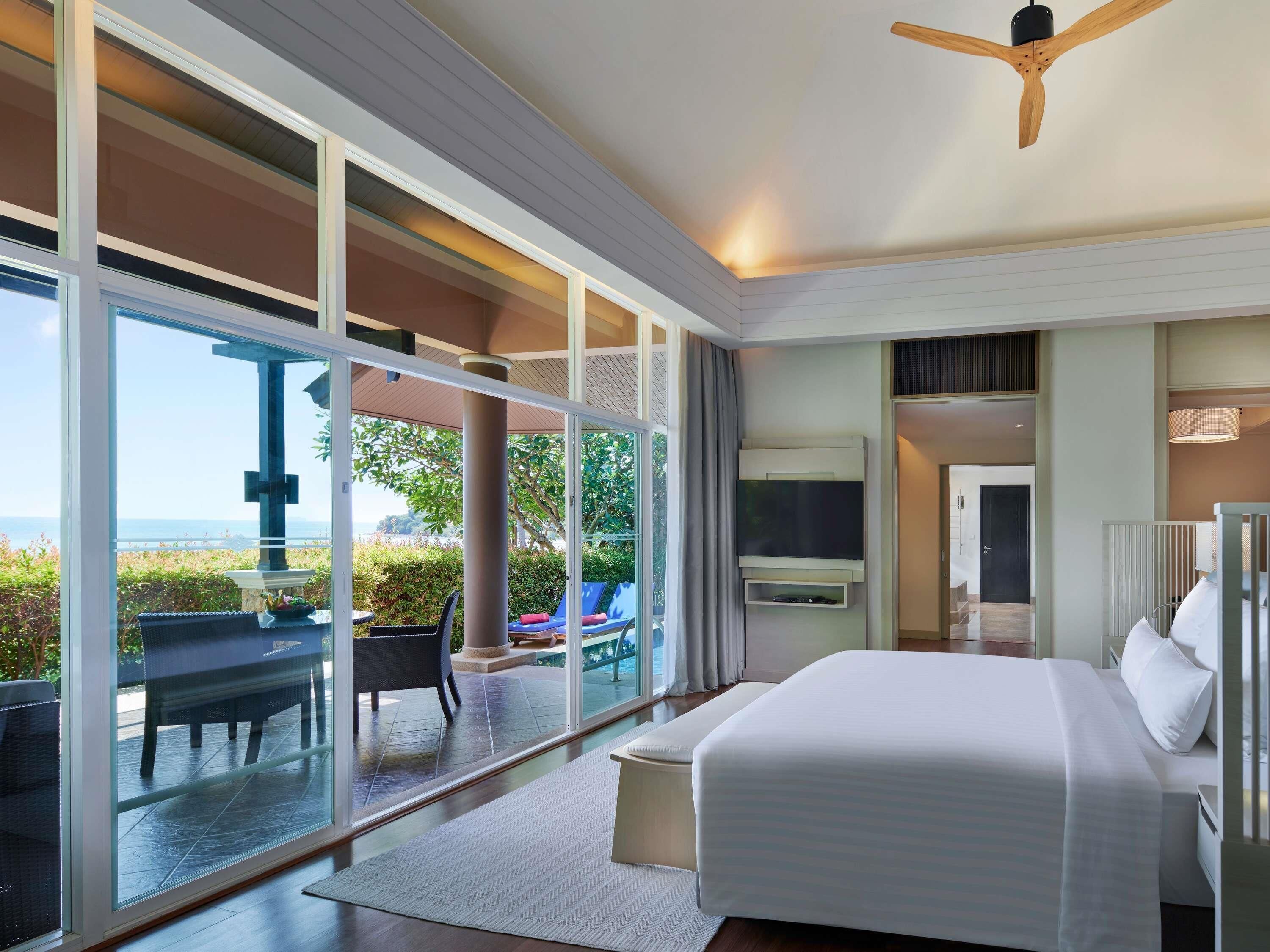 A modern hotel room with a large bed, a TV, and a view of the outdoors.