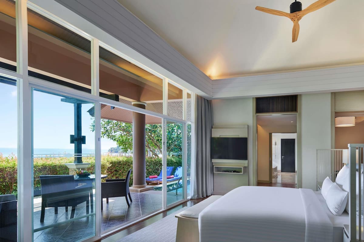 A modern hotel room with a large bed, a TV, and a view of the outdoors.