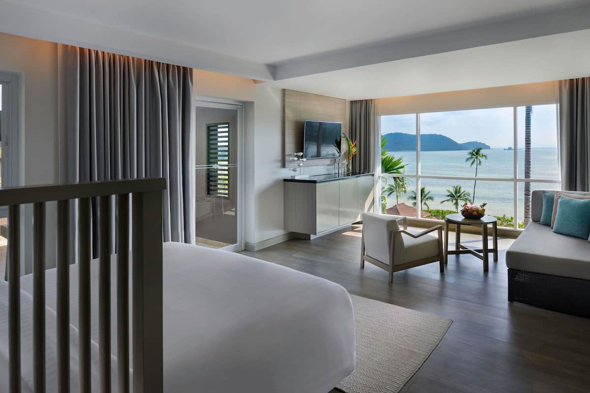 Een hotelkamer met een groot bed, een eethoek, een keuken en uitzicht op zee.