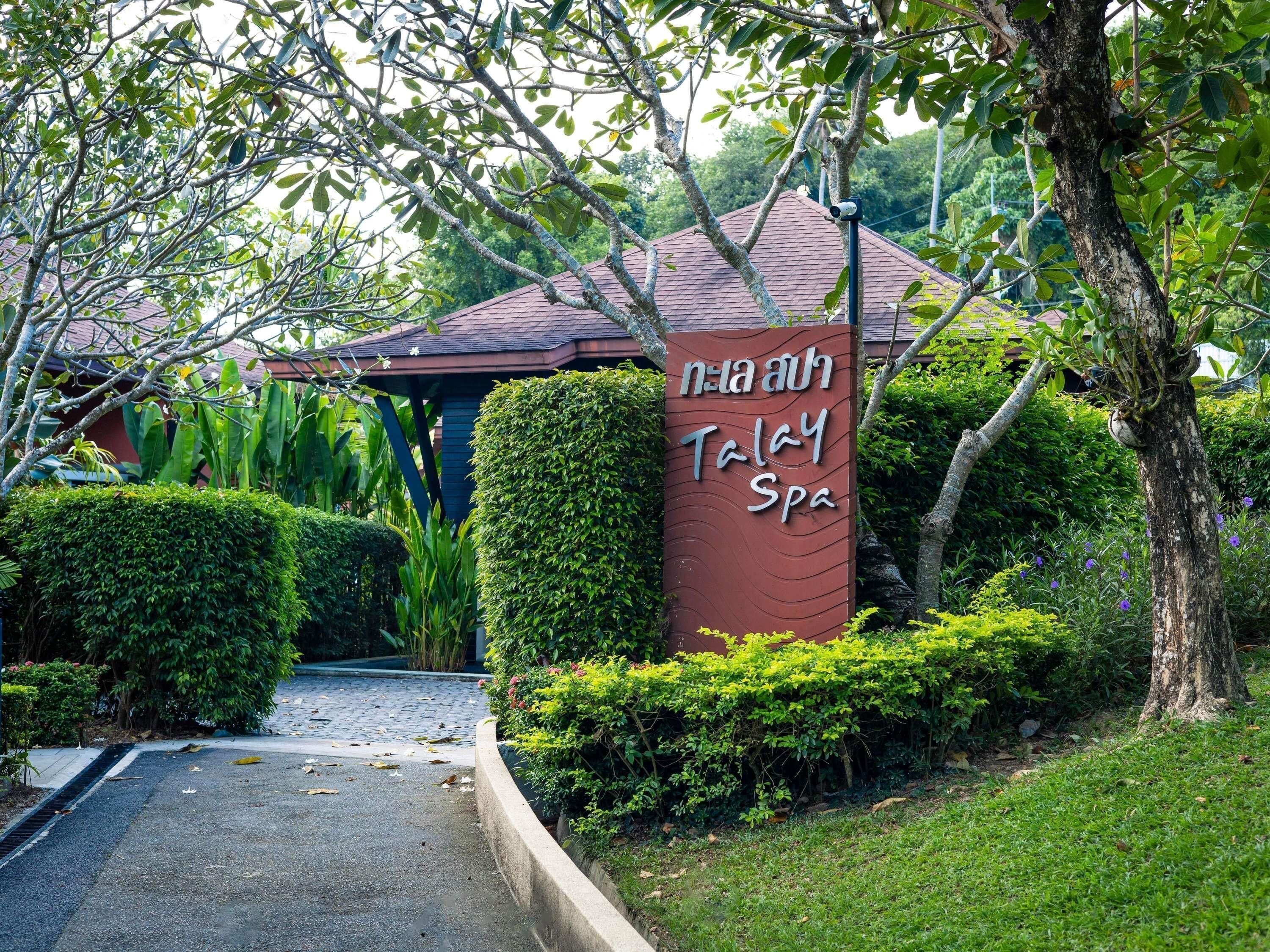 A sign for a spa with a pathway leading to a building surrounded by greenery.