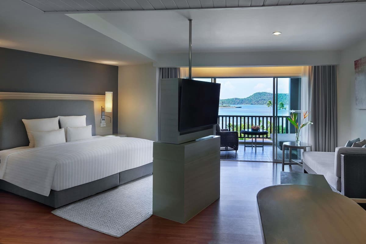 Een hotelkamer met een bed, televisie, balkon en zithoek.