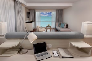 Relax in a stylish room with a large bed, desk, and sofa, offering a sea view.