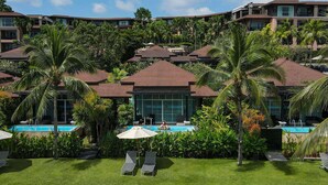 Un resort con varias edificaciones, una piscina y palmeras.