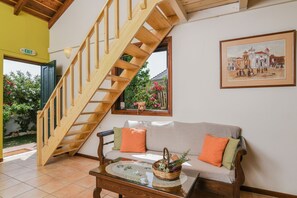 A wooden staircase leading to an upper floor, a sofa with cushions, a glass coffee table, and a framed picture on the wall. - Villas Therianos (Zakynthos)