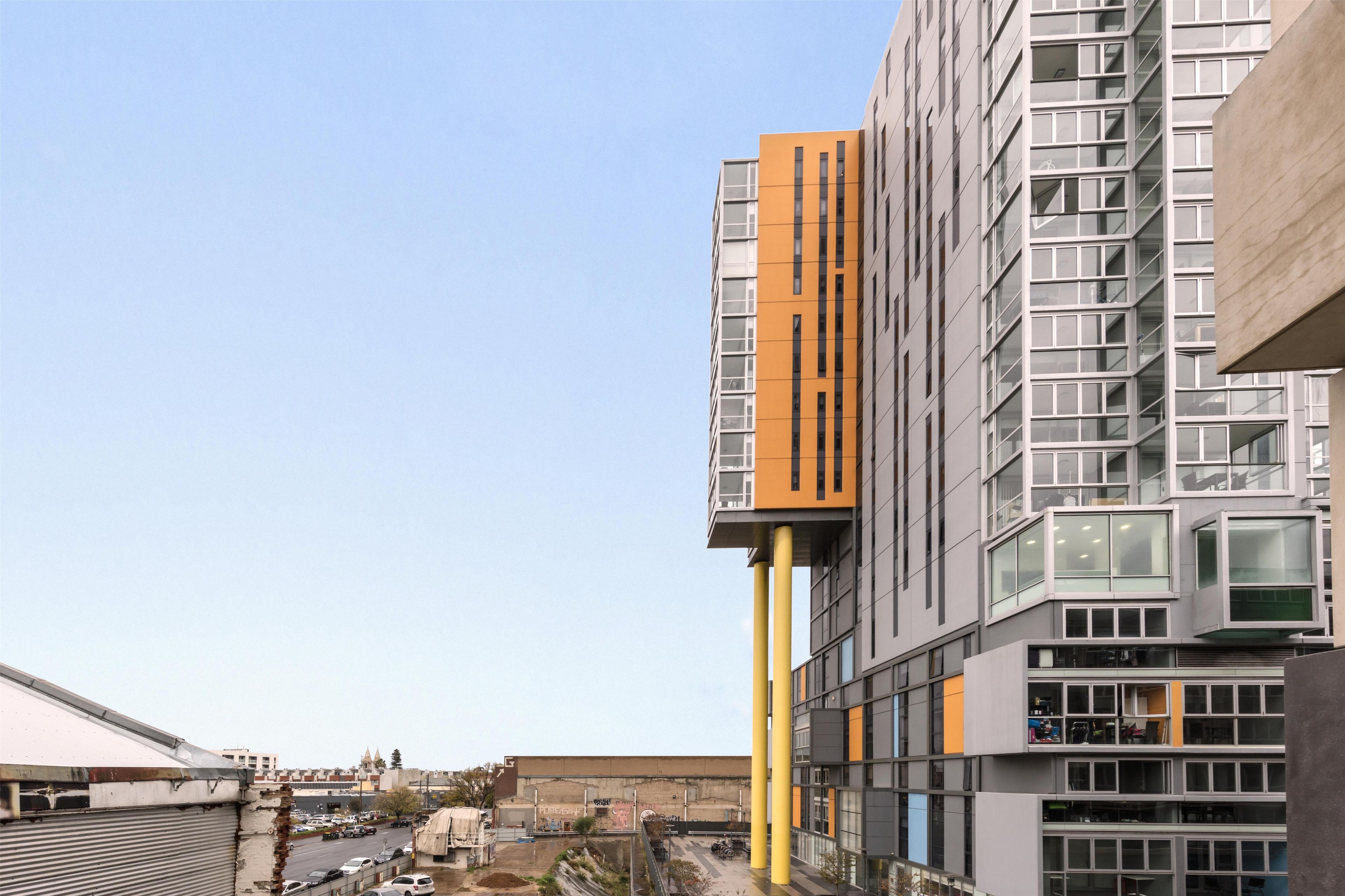 A modern building with multiple floors, large windows, and a distinctive orange and grey facade.