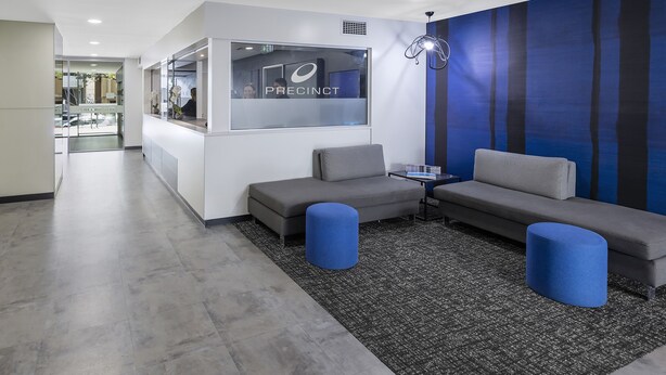 A modern reception area with a white desk, grey sofas, and a blue accent wall. - iStay Precinct Adelaide (Adelaide)