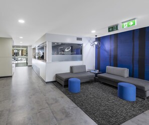 A modern reception area with a white desk, grey sofas, and a blue accent wall.