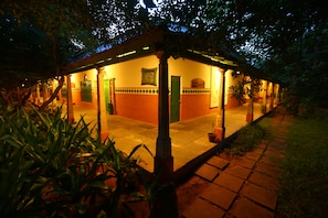 A building with a tiled patio, a green door, and a framed picture on the wall. - Indeco Mahabalipuram (Tirukalukundram)