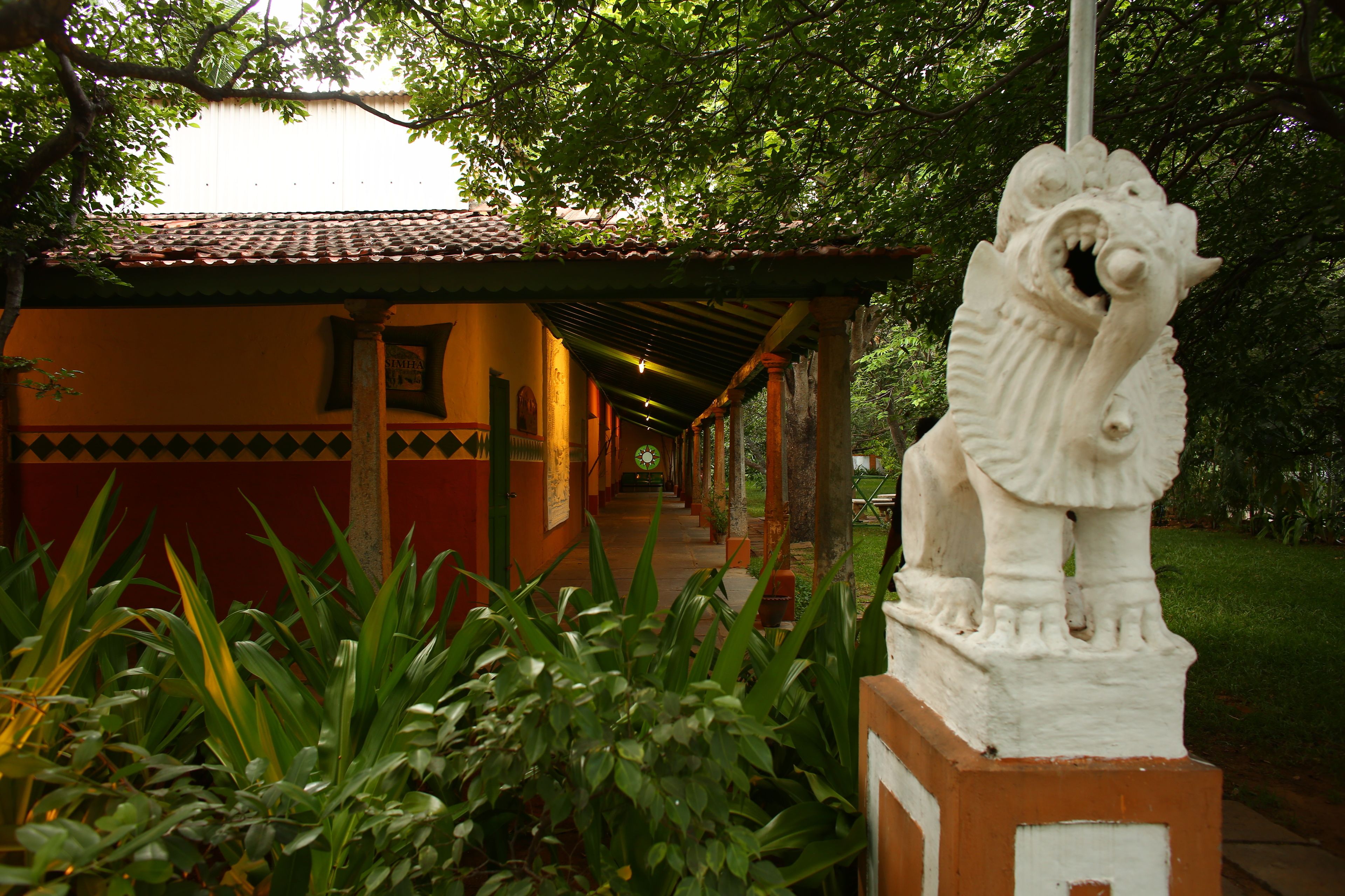 A pathway leading to a building with a tiled roof and a statue of a lion.