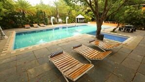 A swimming pool with lounge chairs and a gazebo. - Indeco Mahabalipuram (Tirukalukundram)