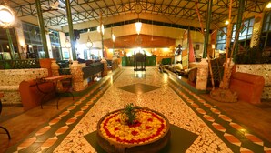 A lobby with a mosaic floor, a central floral arrangement, and seating areas. - Indeco Mahabalipuram (Tirukalukundram)