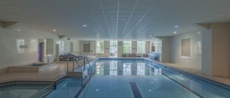 A large indoor swimming pool with clear lanes, a changing room, and a reception area.