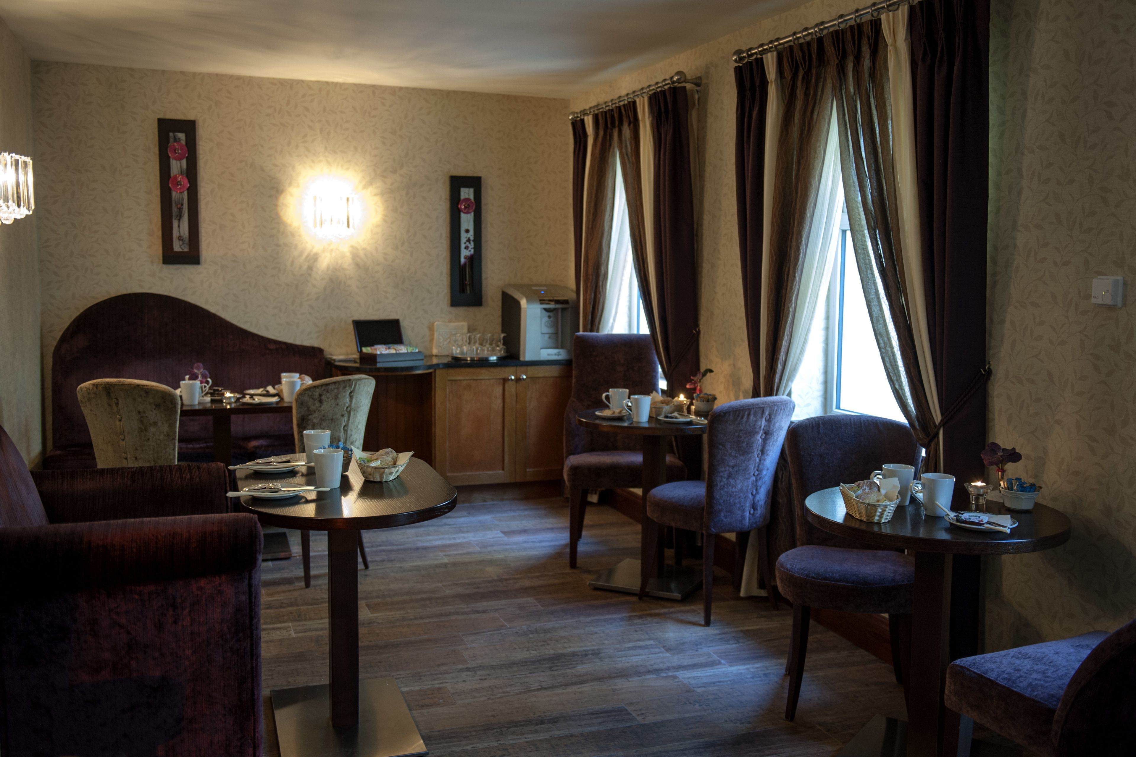 Une chambre d’hôtel comprenant un coin repas, un canapé, un bureau avec un ordinateur et une fenêtre avec des rideaux.