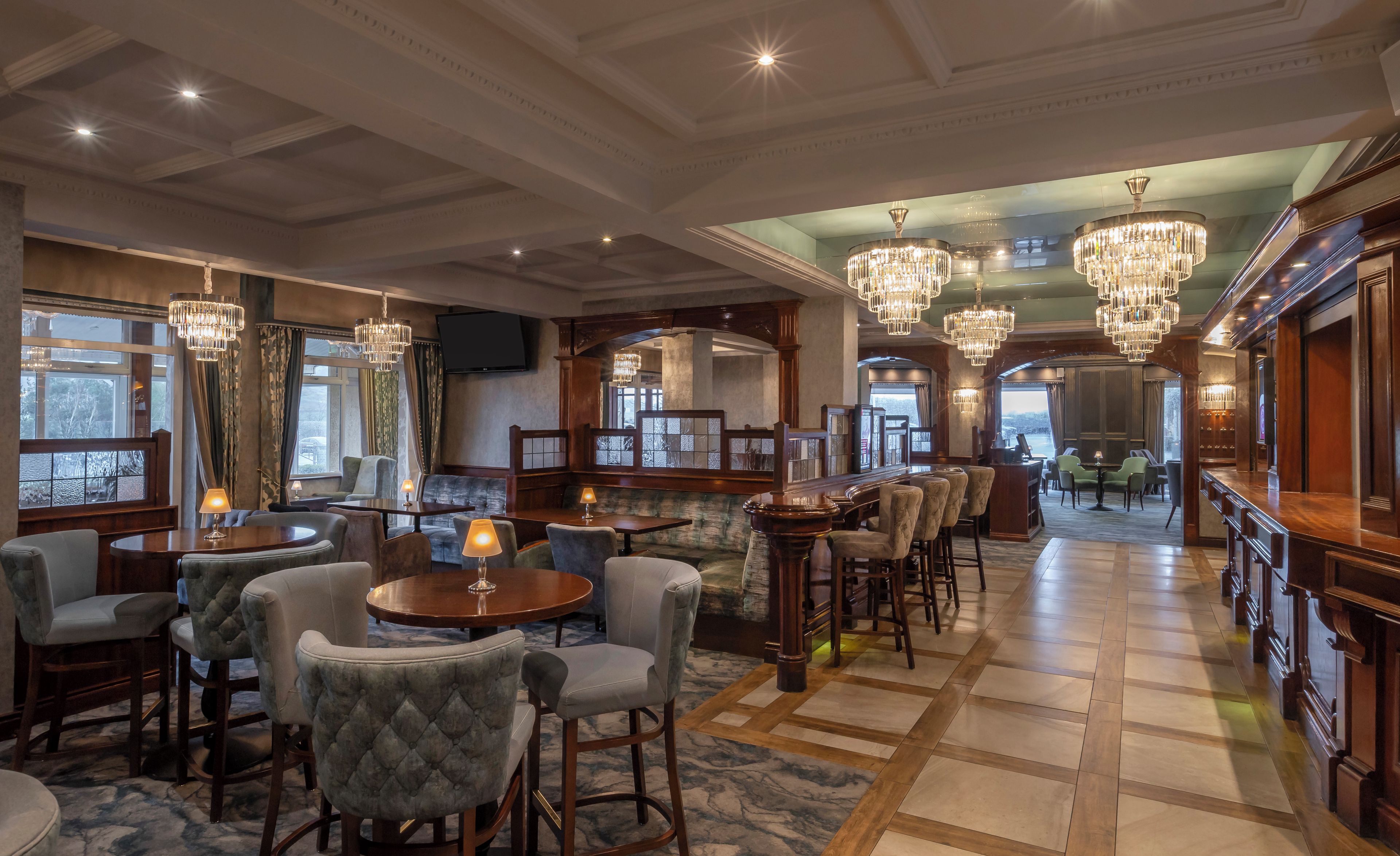 A spacious hotel lobby with a bar area, seating arrangements, and large windows offering views.