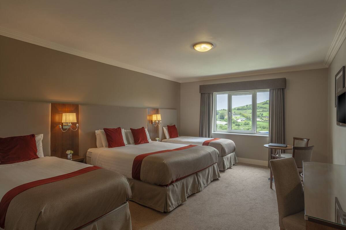 Une chambre d’hôtel avec trois lits, une petite table et un téléviseur.