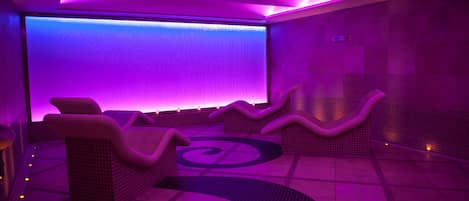 Un cuarto de spa con una zona de estar curvada, una pared grande con un patrón texturizado y un piso de baldosas.