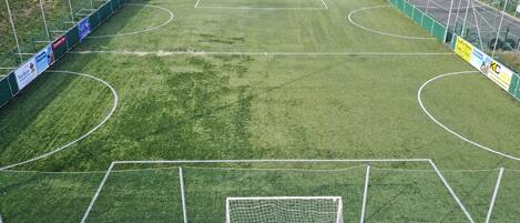 A soccer field with goalposts, advertisements, and a green surrounding fence.