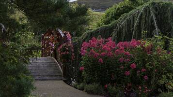 A pathway leading to a gate surrounded by lush greenery and flowering plants.