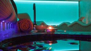 Un área de spa con un jacuzzi, una toalla y una vela.
