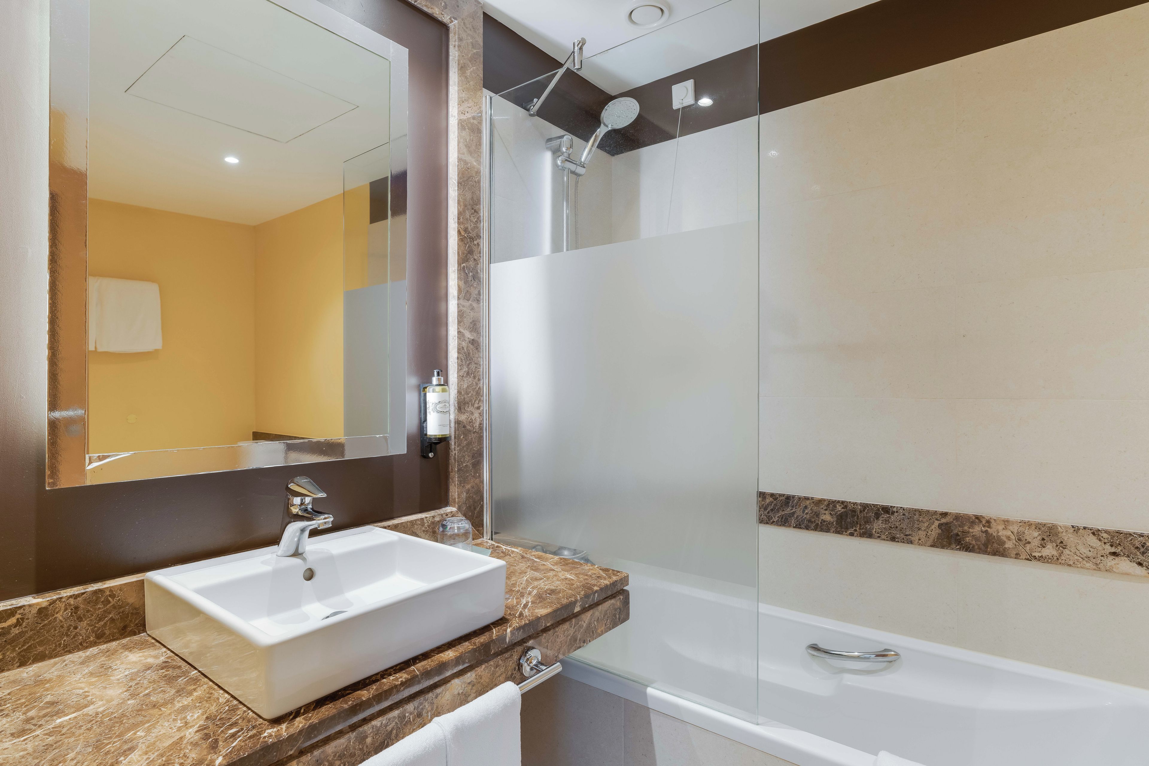 A bathroom with a white sink, a glass-enclosed shower, and a mirror above the sink.