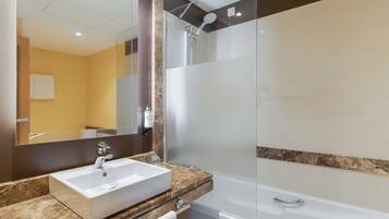 A bathroom with a white sink, a glass-enclosed shower, and a mirror above the sink.