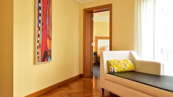 Quarto de hotel com sofá, um quadro na parede e vista através de uma porta aberta.