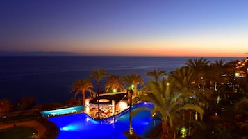 Ein Poolbereich mit Blick auf das Meer im Abendlicht.