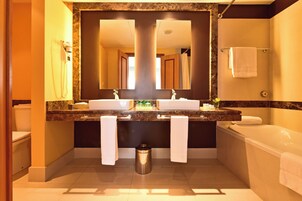 A bathroom with two sinks, a mirror, a toilet, and a bathtub.