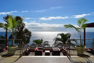 Una terraza con mobiliario exterior y vista al océano.