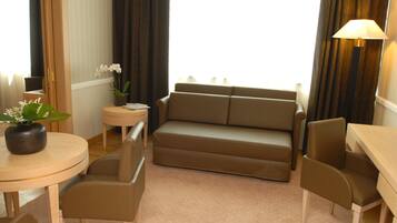 Una sala moderna con un sofá color beige, dos sillones a juego, una mesita redonda con un florero y una lámpara.