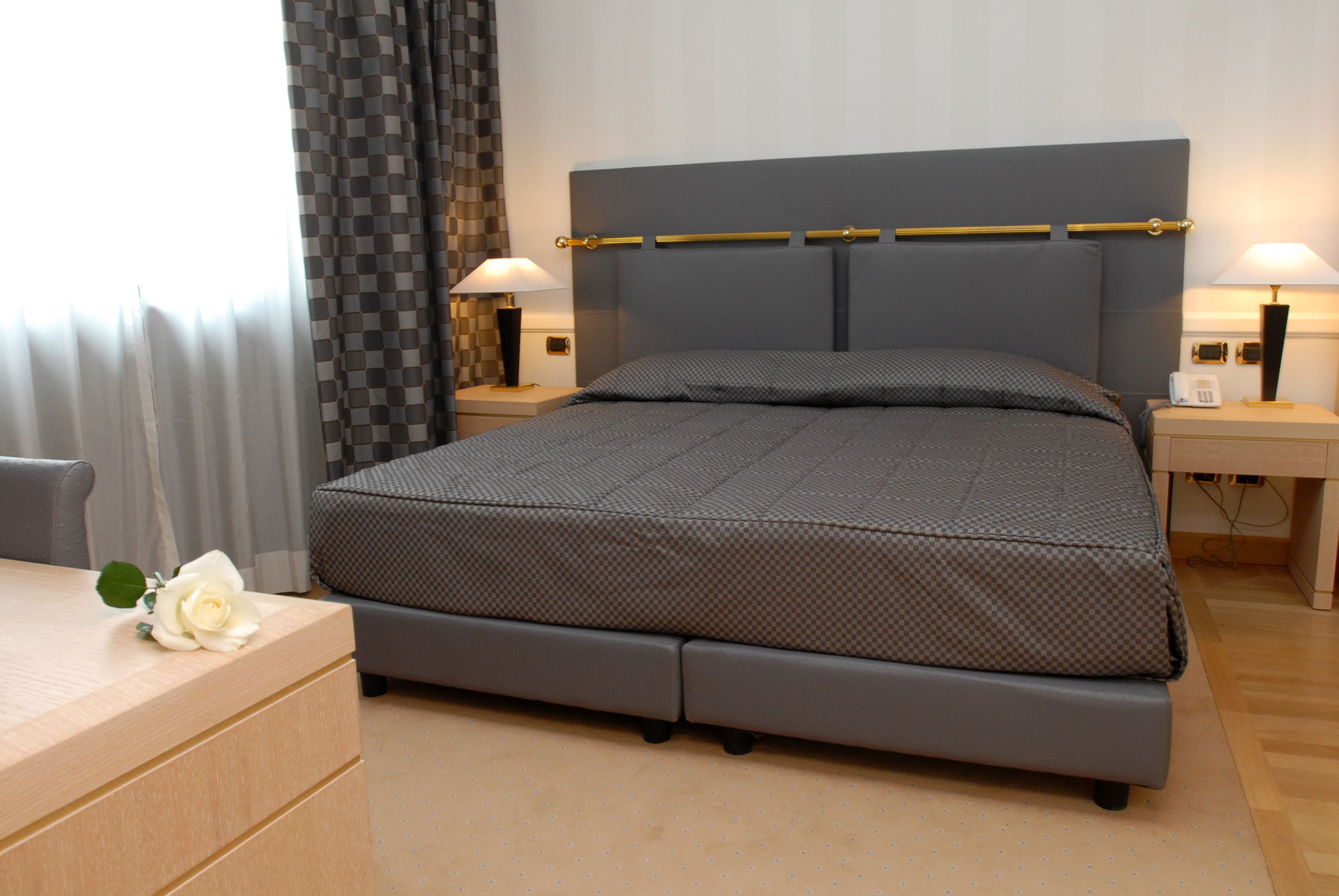 Une chambre à coucher bien rangée, avec un lit, des tables de chevet et un bureau agrémenté d’une fleur.
